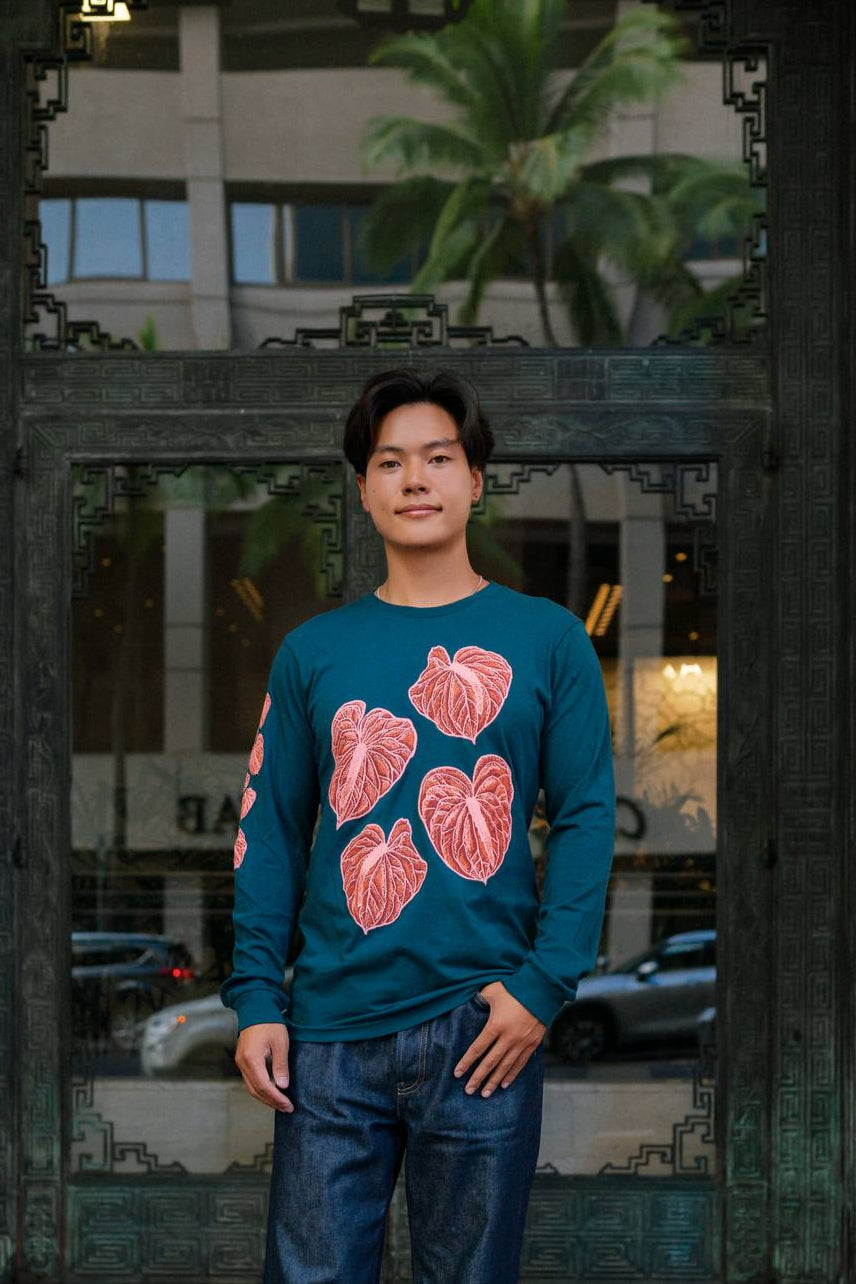 Person wearing a teal sweater with pink floral patterns standing in front of a building entrance.